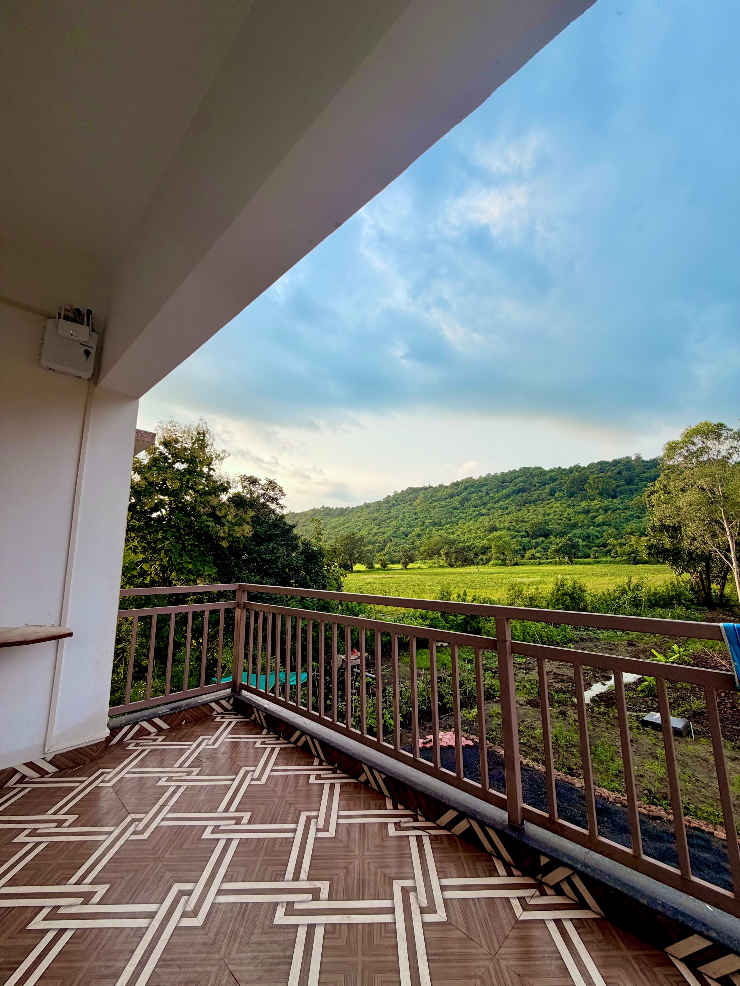 Open sky and a forested hill from the Saanjh balcony.