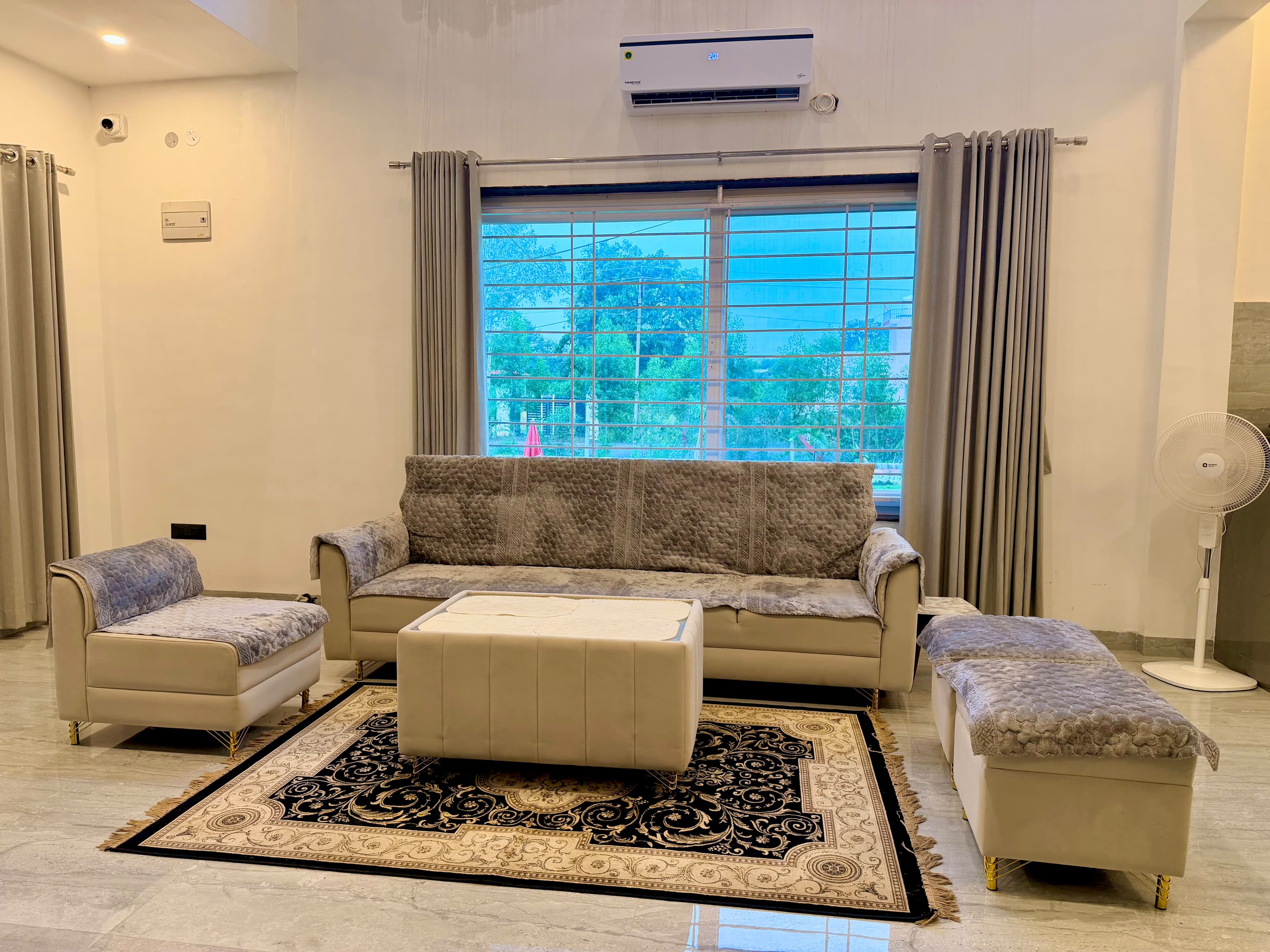 The living room lounge at Saanjh with plush velvet seating, marble floors, and warm natural light.